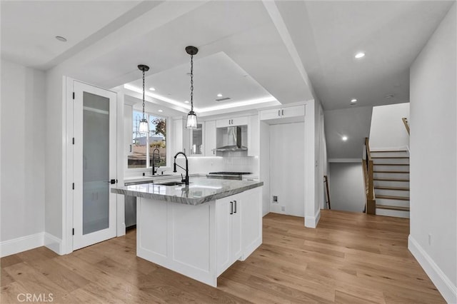 kitchen featuring white cabinetry, a kitchen island, a tray ceiling, and wall chimney exhaust hood