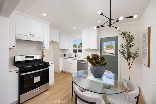 kitchen with pendant lighting, sink, appliances with stainless steel finishes, white cabinetry, and light wood-type flooring