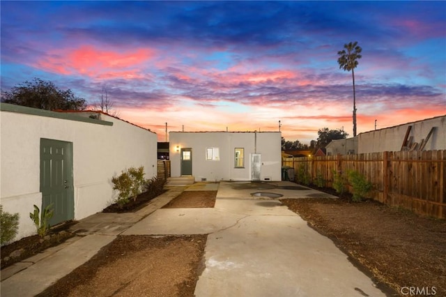 back house at dusk featuring a patio area