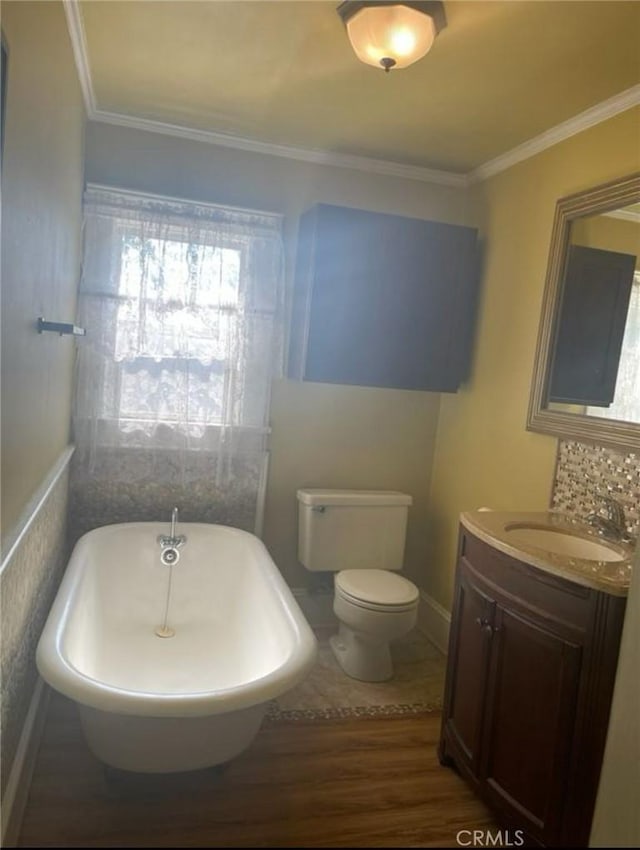 bathroom with hardwood / wood-style flooring, vanity, toilet, crown molding, and a bath