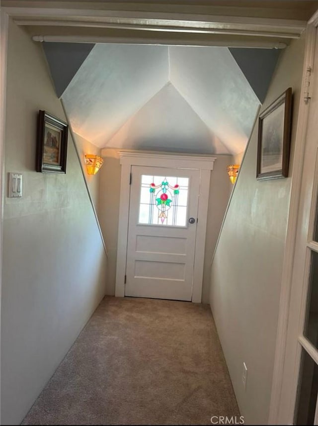 doorway featuring carpet flooring and vaulted ceiling