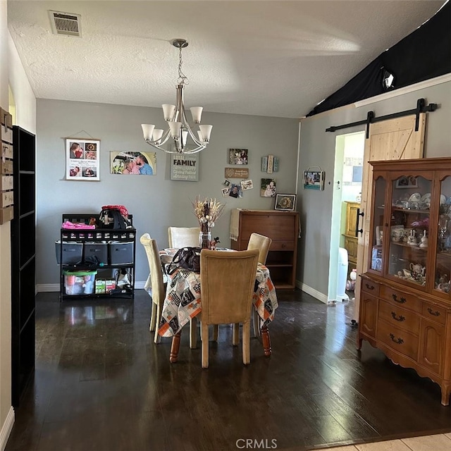 dining space with lofted ceiling, dark hardwood / wood-style flooring, a notable chandelier, a barn door, and a textured ceiling