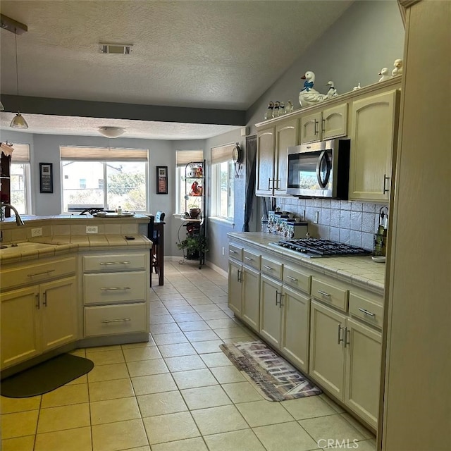 kitchen featuring light tile patterned flooring, appliances with stainless steel finishes, sink, and tile countertops