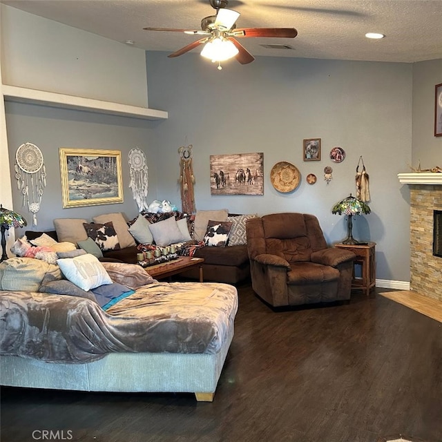 living room with lofted ceiling, dark wood-type flooring, ceiling fan, a fireplace, and a textured ceiling