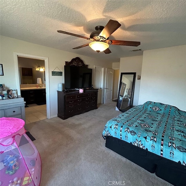 carpeted bedroom with ceiling fan, ensuite bathroom, and a textured ceiling