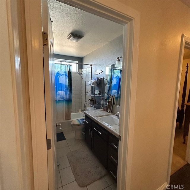 full bathroom featuring tiled shower / bath, tile patterned flooring, vanity, toilet, and a textured ceiling