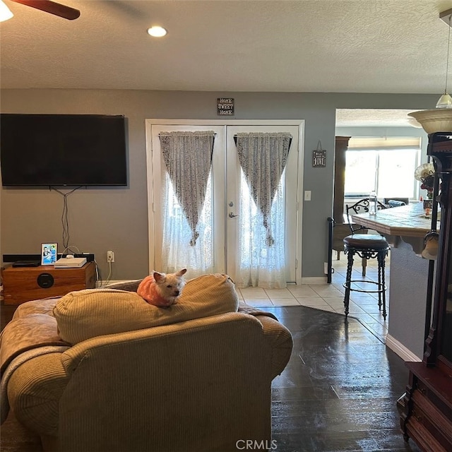 tiled living room featuring ceiling fan, a textured ceiling, and french doors