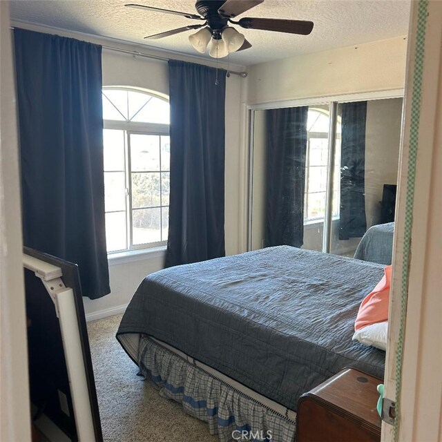 carpeted bedroom with ceiling fan and a textured ceiling