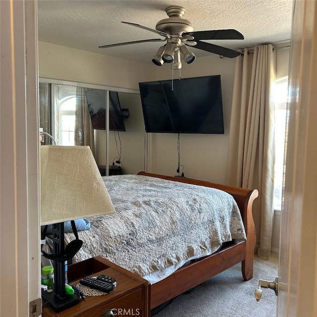 carpeted bedroom featuring ceiling fan and a textured ceiling