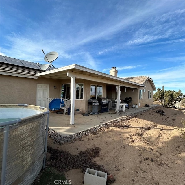 back of house with a patio and solar panels