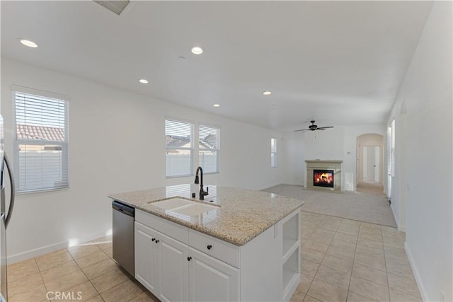 kitchen with dishwasher, an island with sink, sink, white cabinets, and light stone countertops