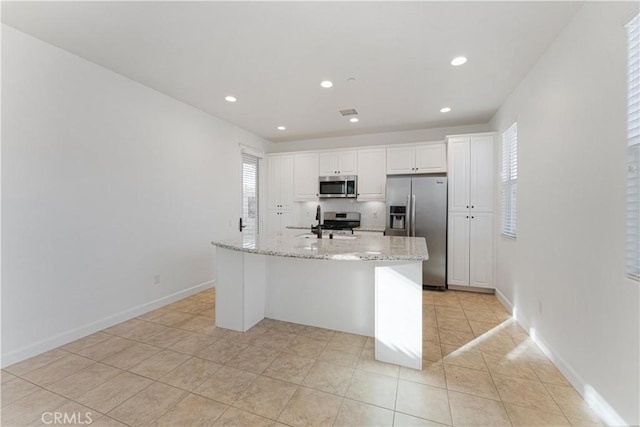 kitchen with white cabinetry, a center island with sink, light stone countertops, and appliances with stainless steel finishes