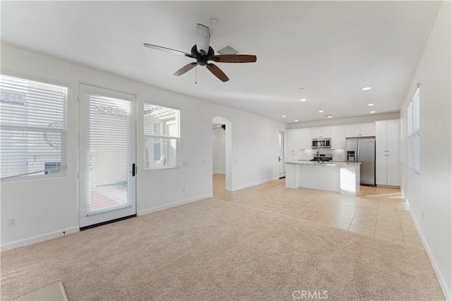 unfurnished living room with light carpet and ceiling fan