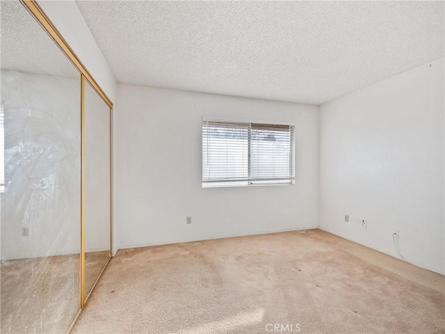 unfurnished bedroom featuring light colored carpet, a closet, and a textured ceiling