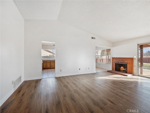 unfurnished living room featuring hardwood / wood-style flooring, a healthy amount of sunlight, and lofted ceiling