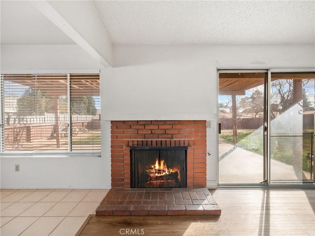 unfurnished living room with a brick fireplace, tile patterned floors, and a textured ceiling