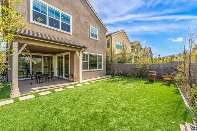 back of house with a yard and a patio