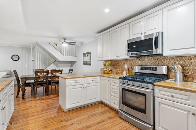 kitchen featuring crown molding, tasteful backsplash, appliances with stainless steel finishes, kitchen peninsula, and white cabinets