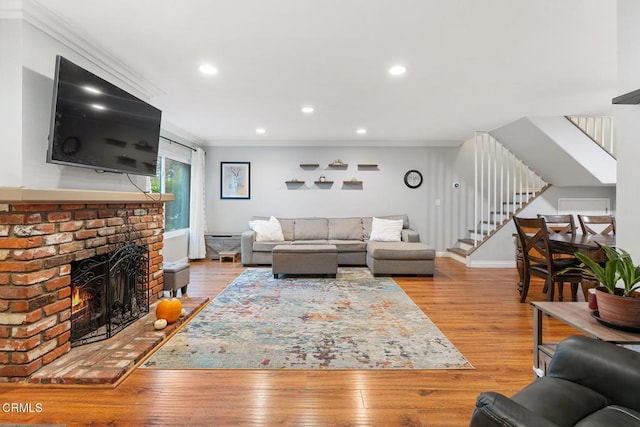 living room featuring ornamental molding, a fireplace, and light wood-type flooring