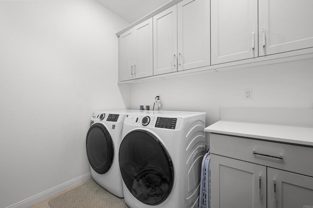 laundry area featuring washer and dryer, cabinets, and light tile patterned floors