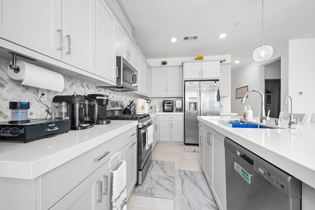 kitchen with appliances with stainless steel finishes, sink, white cabinetry, pendant lighting, and decorative backsplash