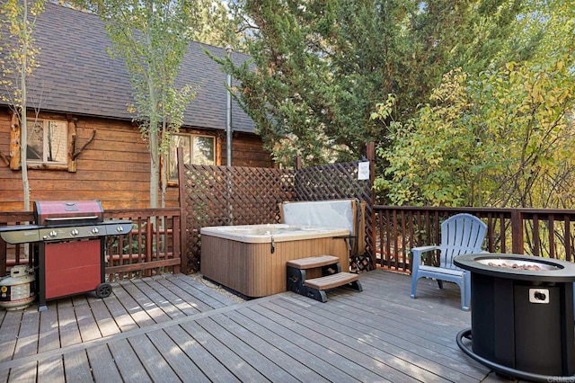 wooden deck with a grill, a fire pit, and a hot tub