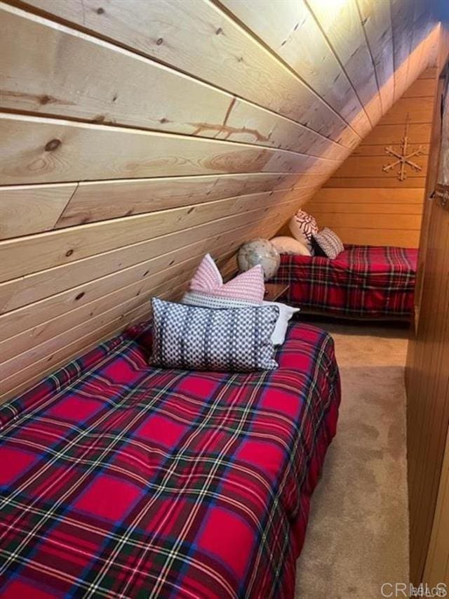 carpeted bedroom featuring lofted ceiling, wood ceiling, and wood walls