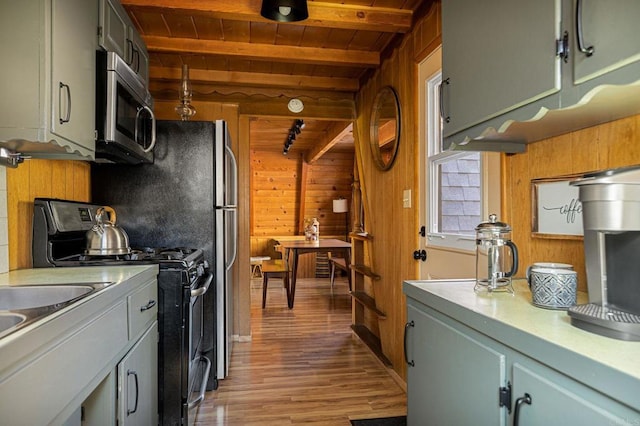 kitchen with wood ceiling, range with electric stovetop, wooden walls, beamed ceiling, and light hardwood / wood-style floors