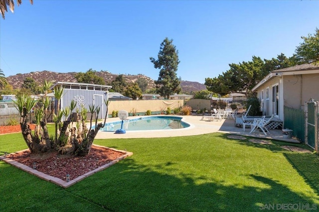 view of pool featuring a storage unit, a yard, a mountain view, and a patio area