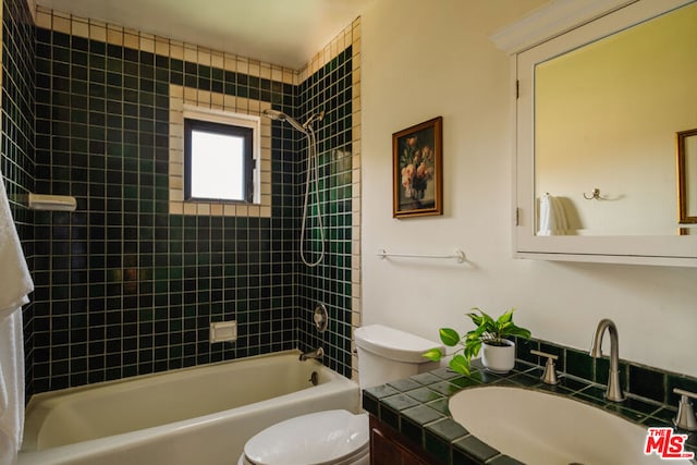 full bathroom with tiled shower / bath, vanity, and toilet