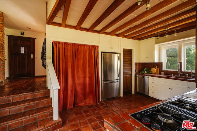 kitchen featuring white cabinetry, sink, decorative backsplash, stainless steel appliances, and beam ceiling