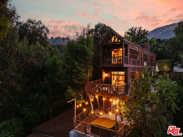 back house at dusk with a balcony and a mountain view