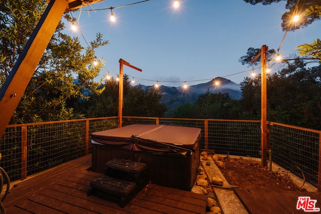 deck at dusk featuring a hot tub