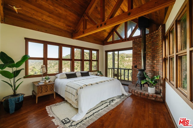 bedroom with access to exterior, dark hardwood / wood-style floors, wooden ceiling, beamed ceiling, and a wood stove