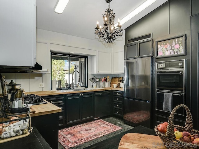 kitchen with butcher block countertops, sink, white cabinetry, hanging light fixtures, and black appliances