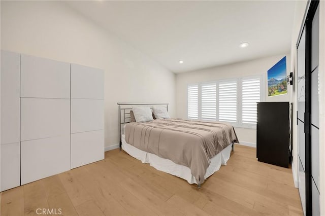 bedroom with lofted ceiling and light hardwood / wood-style floors