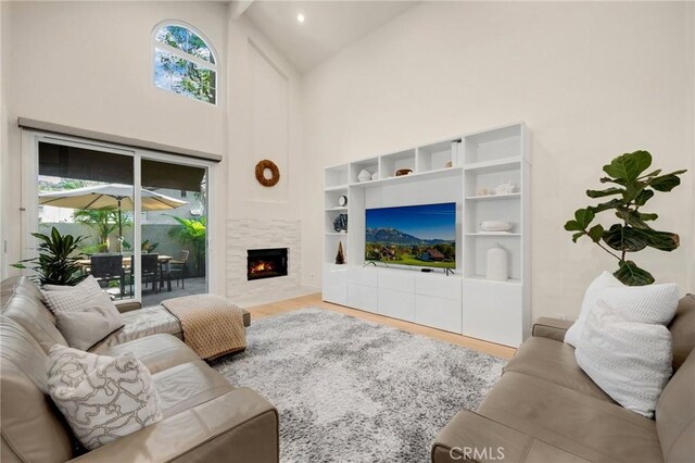 living room with high vaulted ceiling, hardwood / wood-style flooring, and a tile fireplace