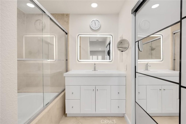 bathroom featuring vanity, tile patterned flooring, and enclosed tub / shower combo