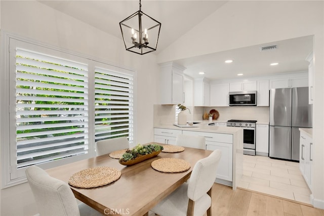 tiled dining area featuring vaulted ceiling, a wealth of natural light, and an inviting chandelier