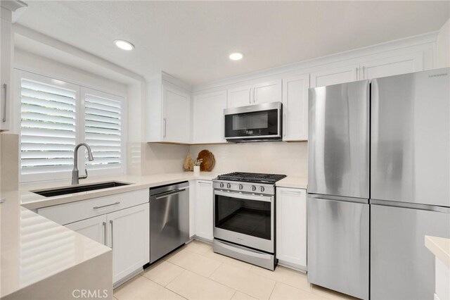 kitchen featuring light tile patterned floors, appliances with stainless steel finishes, sink, and white cabinets