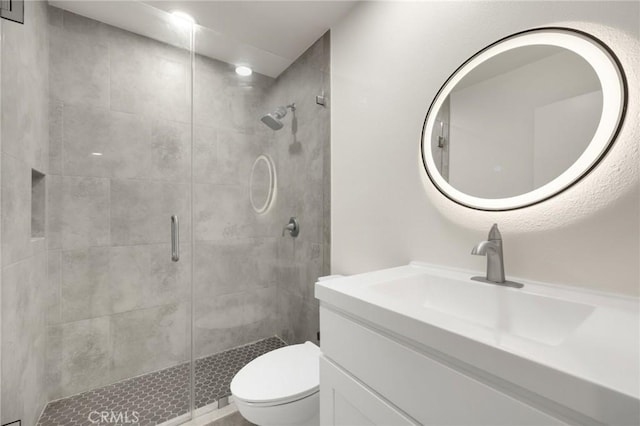 bathroom featuring vanity, a shower with door, and toilet