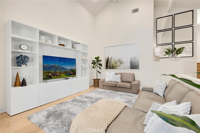 living room featuring beam ceiling, high vaulted ceiling, and light wood-type flooring