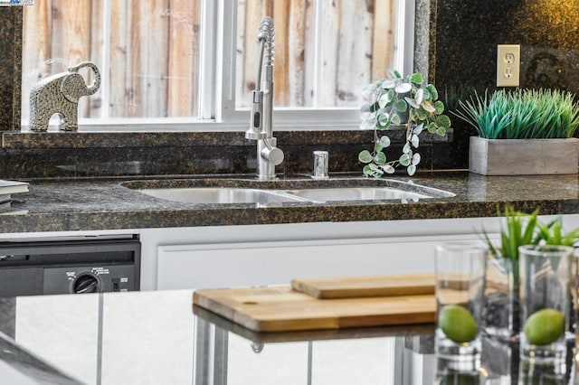 details with white cabinetry, sink, and dark stone countertops