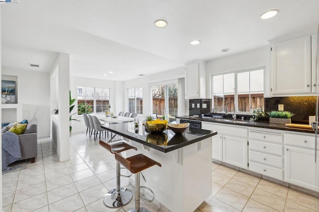 kitchen featuring a kitchen bar, sink, a kitchen island, and white cabinets