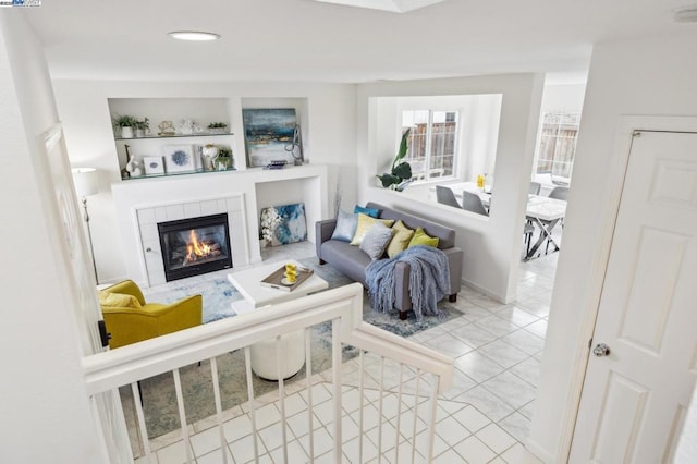 living room with a fireplace, built in features, and light tile patterned floors