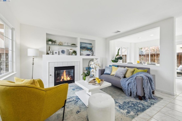 living room with light tile patterned flooring, a fireplace, and built in features