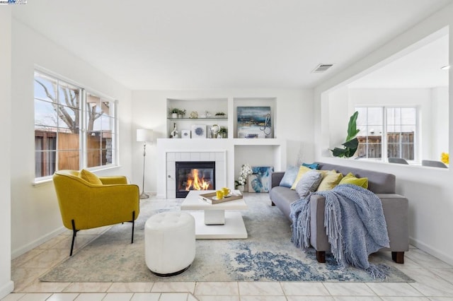 tiled living room featuring built in shelves and a tile fireplace