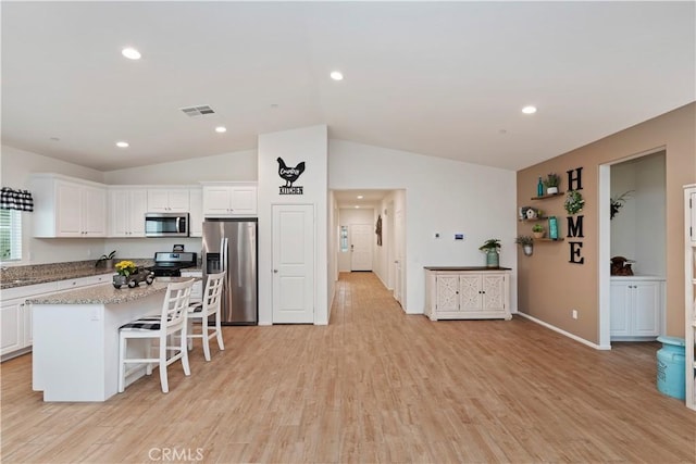 kitchen featuring white cabinetry, a kitchen breakfast bar, a center island, stainless steel appliances, and light stone countertops