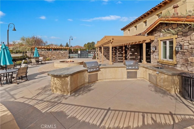 view of patio with a grill, a fire pit, sink, and exterior kitchen