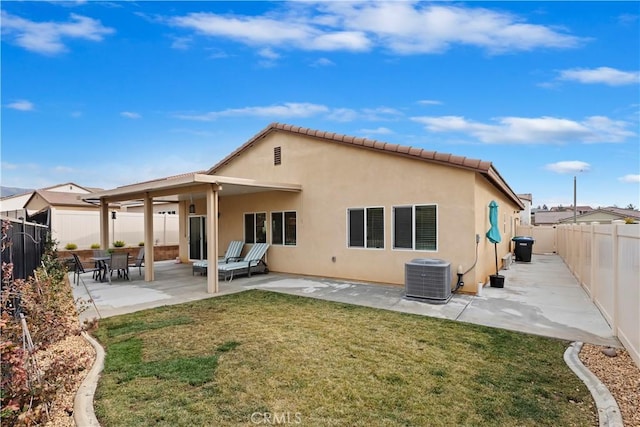 rear view of house featuring cooling unit, a patio area, and a lawn